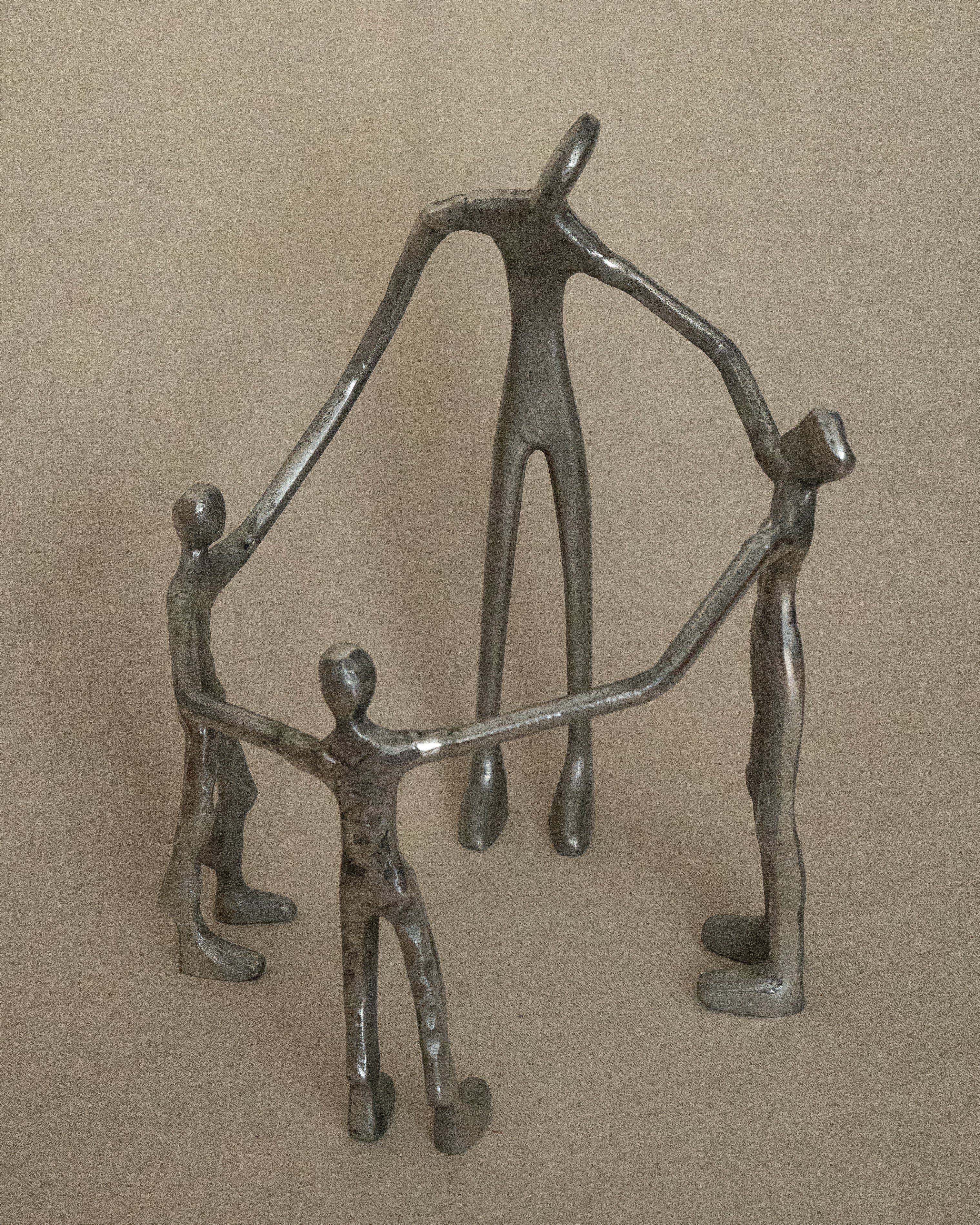 4 aluminum humans holding hands in a circle