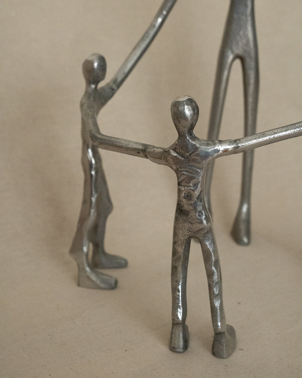 4 aluminum humans holding hands in a circle