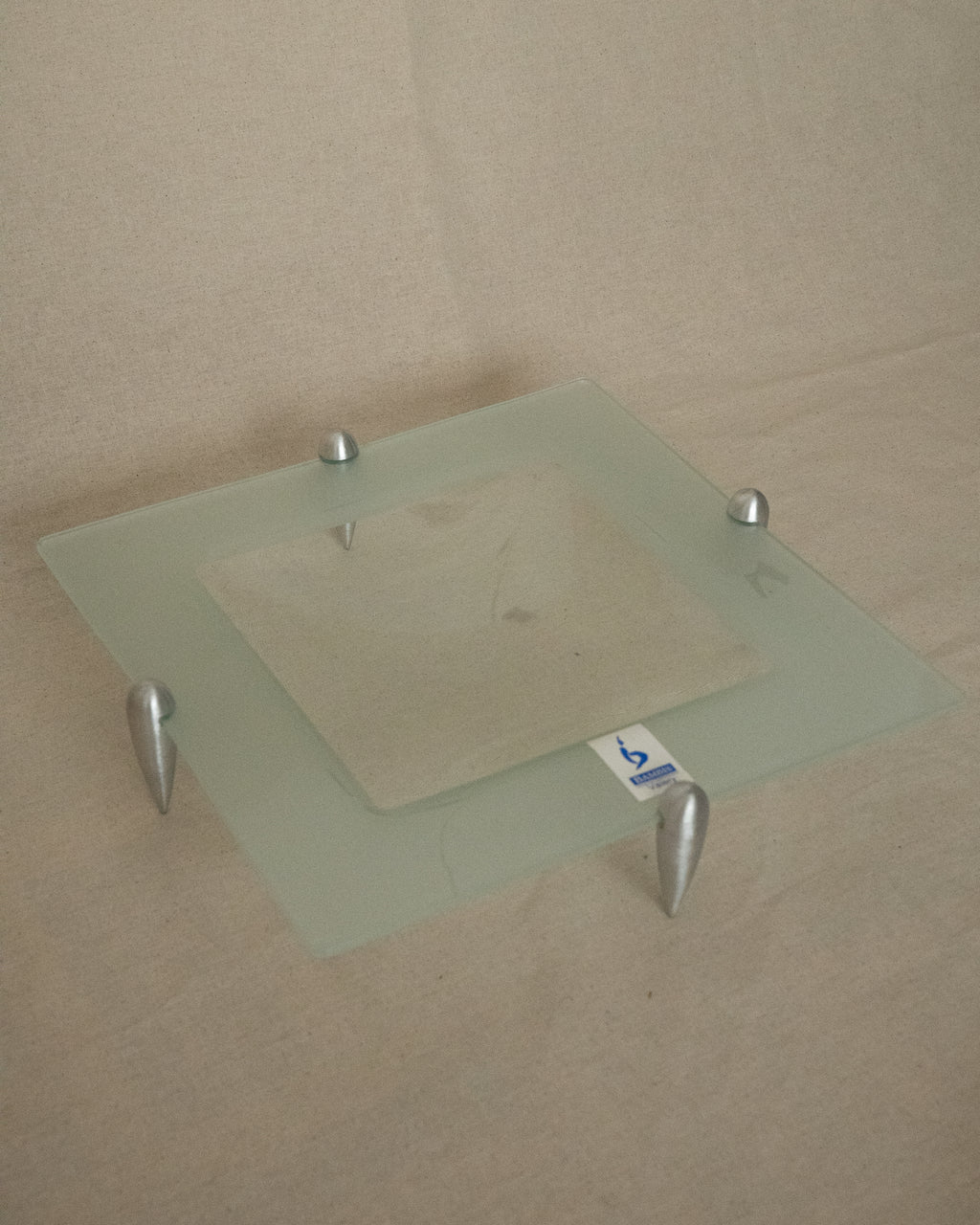 Glass square dish raised by atomic silver feet