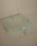 Glass square dish raised by atomic silver feet