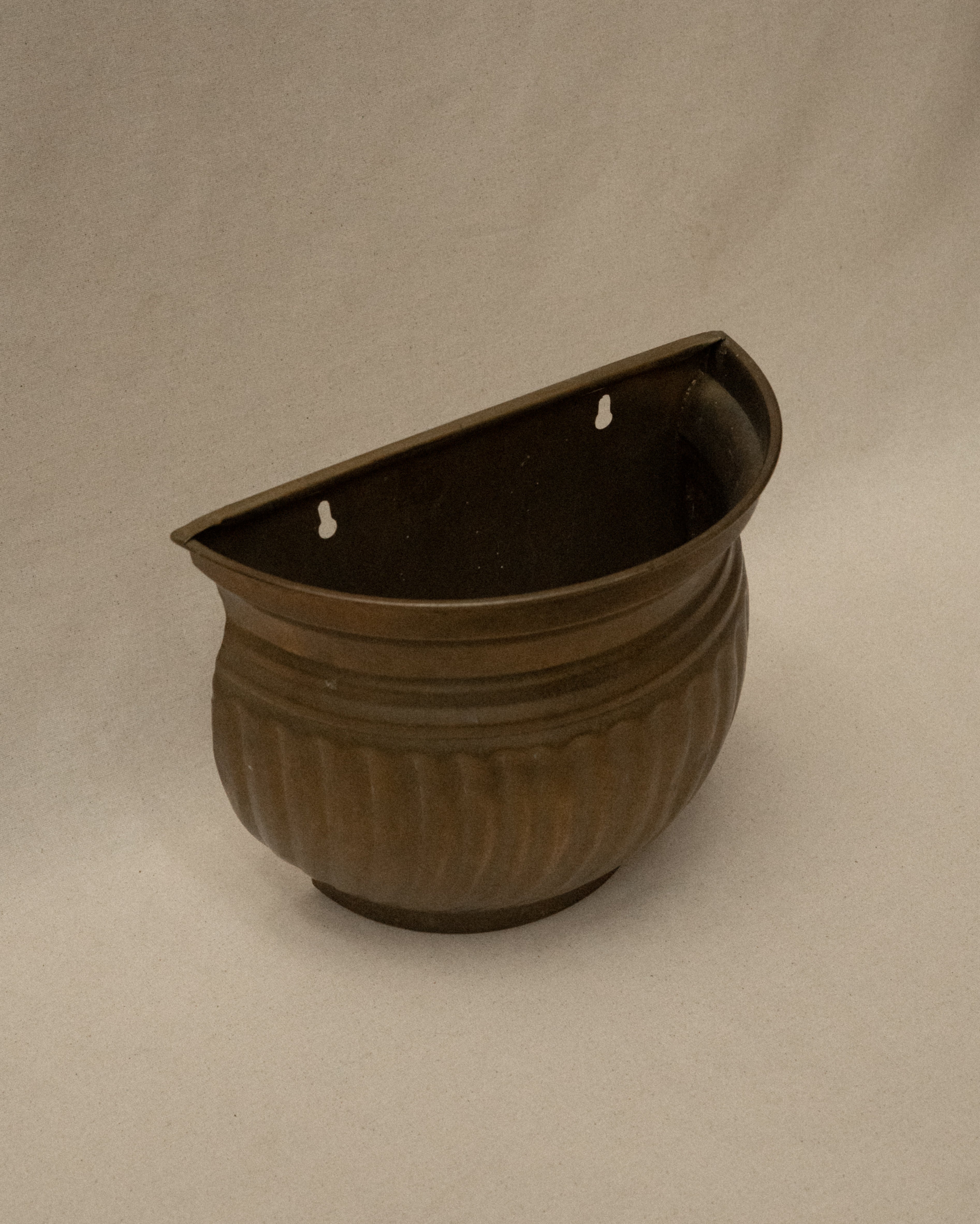 Brass plant pot that hangs on a wall