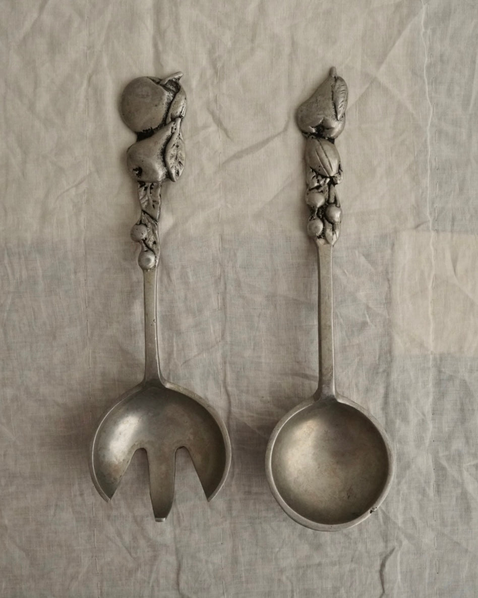 A pair of large metal serving utensils with fruit handles