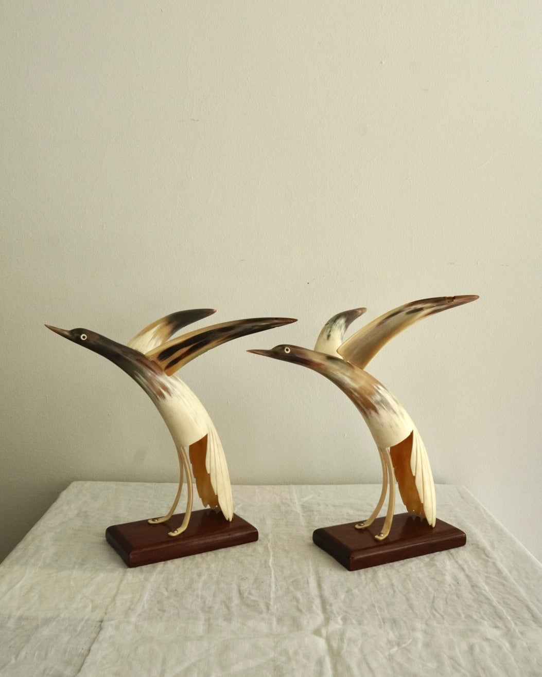 Pair of carved horn duck sculptures on a wooden base